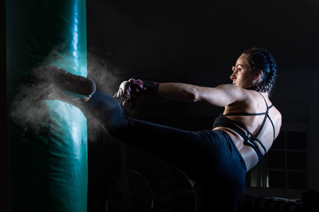 young female boxer punching a bag on a sports training in a gym.